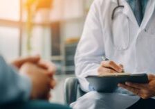Two doctors in consultation writing on a patient chart as part of the ACO REACH care coordination model at ASAAR Medical.